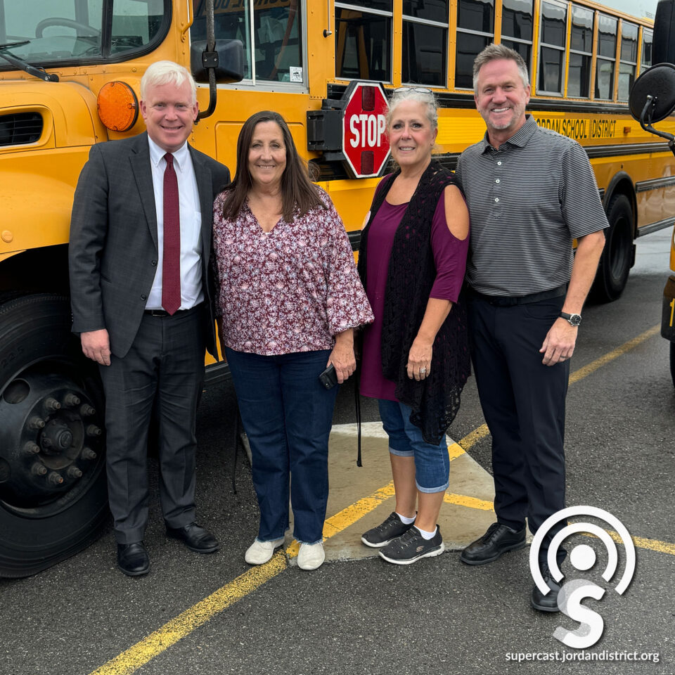 Superintendent and transportation staff in front of a bus